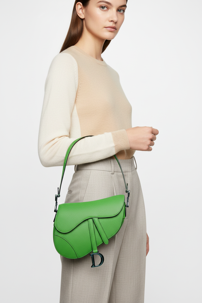 Model holding Dior Green Saddle Bag with extremely short strap